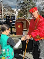 A girl scout hands over a package of cookies to a local veteran.