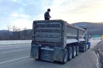 Environmental Conservation Officer Obadiah Steffen climbs into a tractor trailer to inspect fill material.