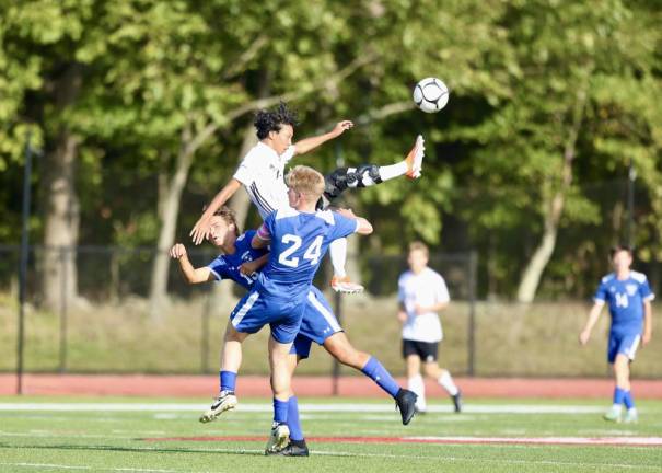 Crusader Jaxon Yamamoto (in white) flies high between two Gladiator defenders to get a foot on the ball.