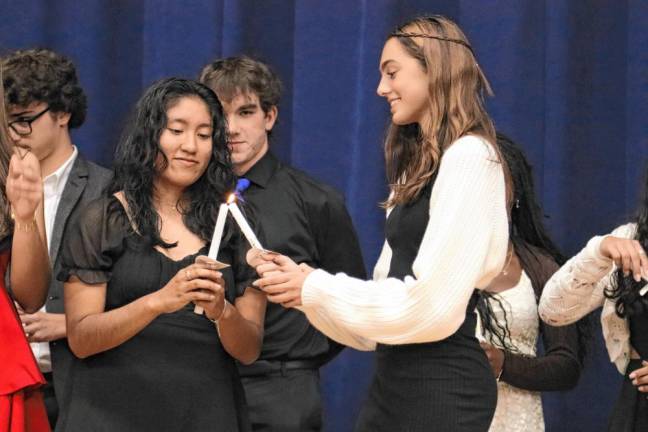 One student lights the candle of another student during the ceremony.