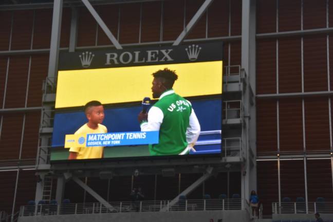 Albert Ji, 9, fields questions while his peers from summer camp at Matchpoint Tennis rally on the Louis Armstrong Stadium court.